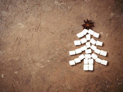 Christmas food and drink background. Christmas tree made from marshmallow and star anise on brown