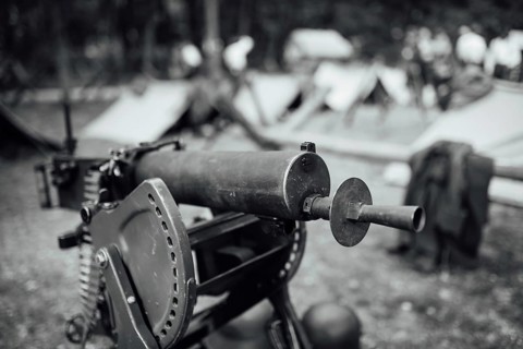 A heavy machine gun from I Word War with a military camp in the background