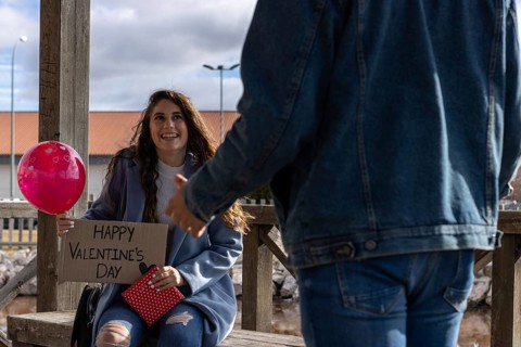 Young woman with a happy valentine's day sign, a balloon of hearts and a red gift, giving a