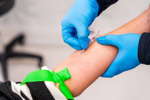 Close-up of nurse using needle to extract blood sample from a woman