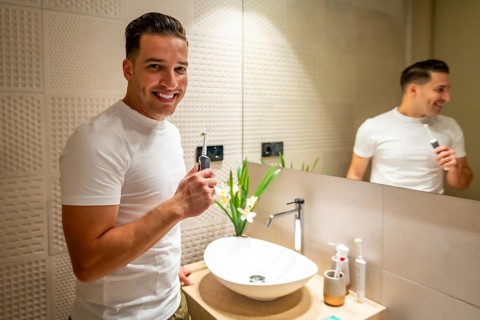 Man smiling at camera after cleaning his teeth in the bathroom