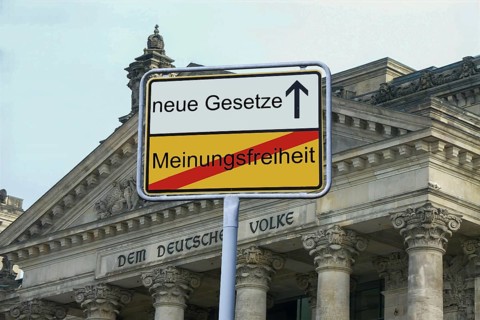 (Photomontage) : Exit sign in front of the inscription NEUE GESETZE / MEINUNGSFREIHEIT in front of