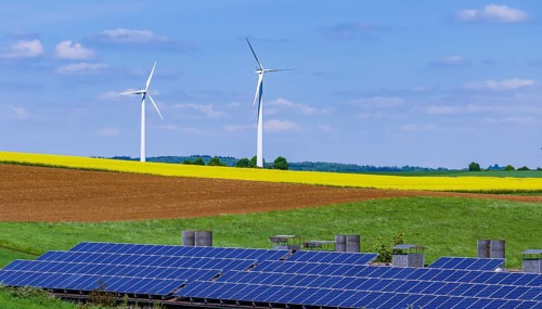Landscape of the Swabian Alb in spring with rape field and wind turbines. In front of it a building