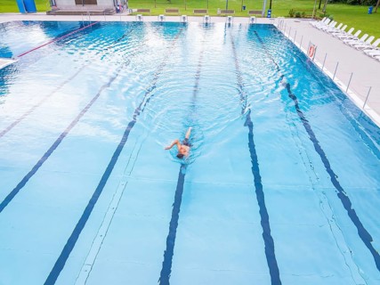 A swimmer moves in an almost empty swimming pool with clear lanes, Calw outdoor pool, Black Forest,