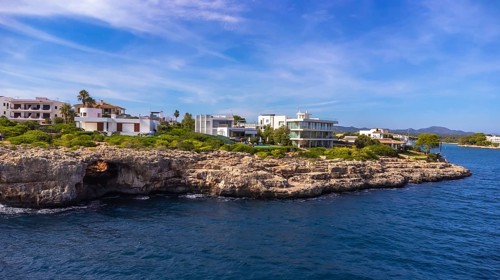 Stunning aerial view of the portocolom lighthouse and luxury villas perched on a rocky coastline in