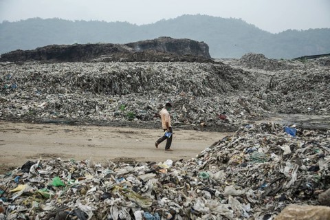A person walking between garbage heap at a garbage dumpsite in the eve of World Environment Day, in