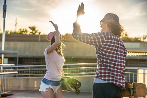 Two friends sharing a joyful high five after an exhilarating longboarding session, basking in the