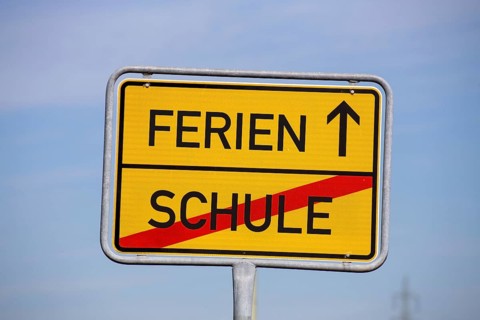 (Photomontage) Symbolic image summer holidays: Town exit sign with text HOLIDAYS and SCHOOL