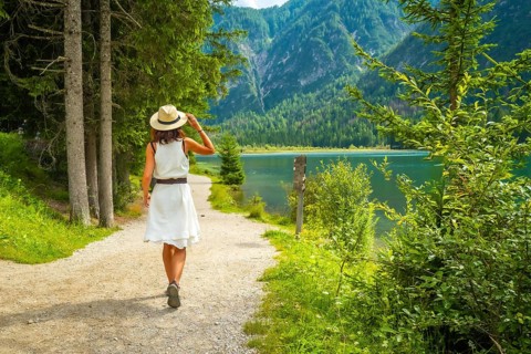 Tourist walking on a path near lake dobbiaco, enjoying the summer landscape in the dolomites