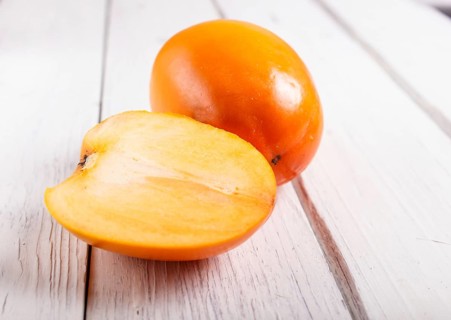 Ripe orange persimmon on white wooden background, with copy space, top view