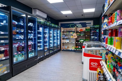 Modern supermarket with illuminated refrigerated shelves and numerous products, Tante M,
