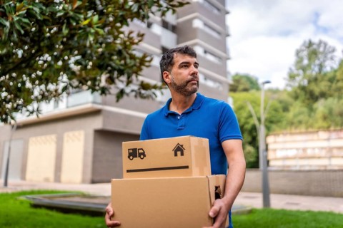Handsome delivery man with boxes in his hands, working and walking along the city