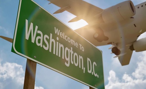 Welcome to washington D.C. road sign against a blue sky and clouds with low flying airplane above