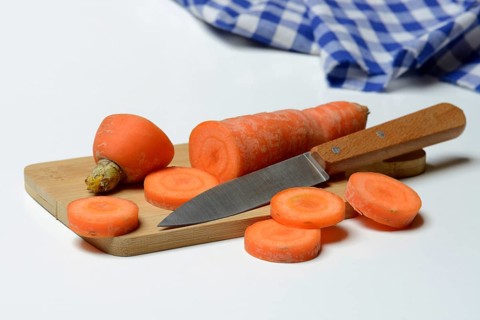 Carrot, carrot slices with kitchen knife on wooden board