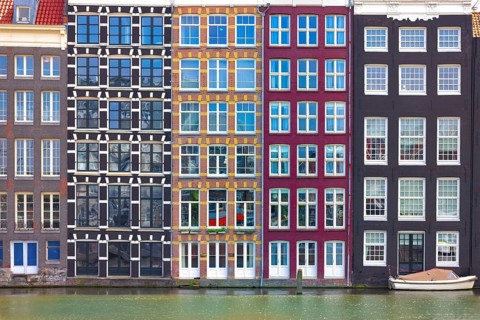 Holland, Amsterdam Damrak canal houses with scenic bridges in historic center, UNESCO Heritage site
