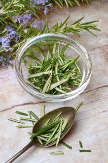 Rosemary, plucked rosemary leaves in a glass bowl and flowering sprig