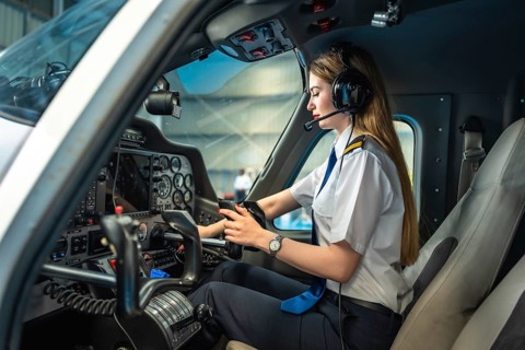 Confident female pilot using electronic flight bag while sitting in cockpit of small airplane