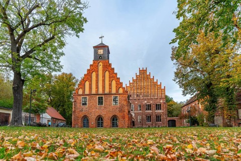 Autumn atmosphere with leaves in the meadow in front of Zinna Monastery with its brick