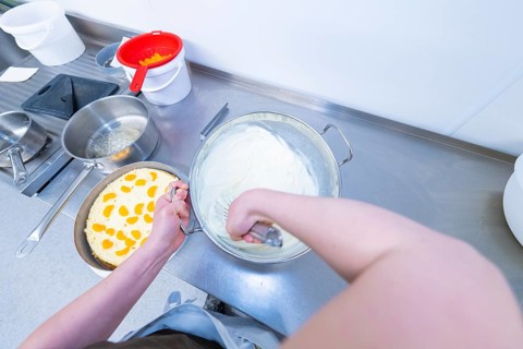 Person preparing cream in a bowl next to a cake base, cake baking, Haselstaller Hof Cafe Kuh,