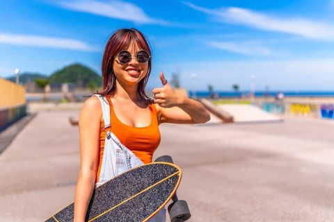 Young urban chinese woman gesturing confidence with thumb up in skateboard park