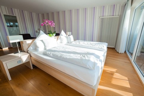 Bright bedroom with double bed, wooden floor and purple striped walls, Hotel Krone Lamm,