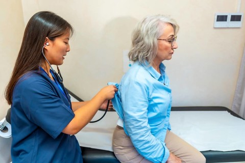 Female doctor examining the lungs of a senior woman with a stethoscope during a routine medical