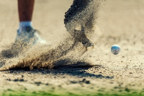 A golf ball is hit out of the bunker