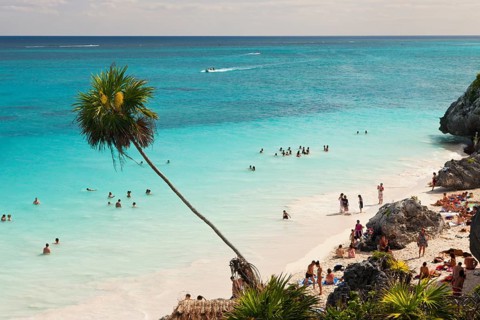 Tourists on the beach in front of the Mayan ruins of Tulum, Riviera Maya, Yucatan Peninsula,