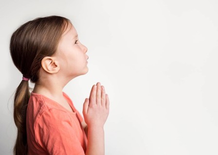 Beautiful little girl praying with copy space