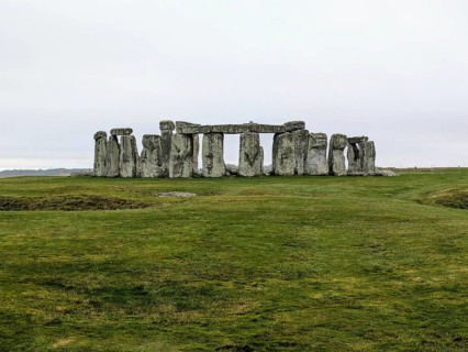 Distant view of Stonehenge surrounded by green grass under an overcast sky. Salisbury, England,