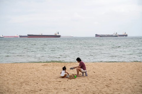 31.07.2023, Singapore, Republic of Singapore, Asia, A woman and a small child sit in the sand on