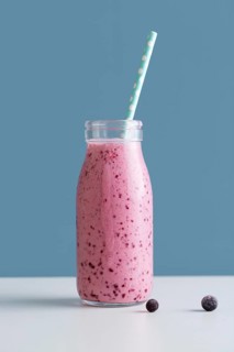 Front view pink smoothie bottle with straw blueberries
