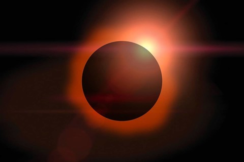 Solar eclipse with orange halo on black sky background