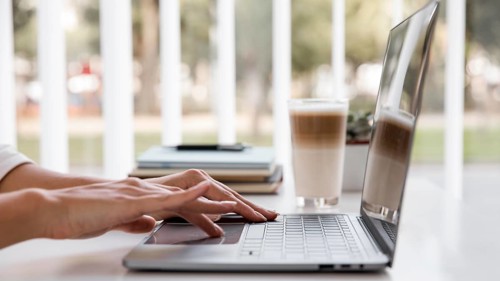 Side view businesswoman working with laptop having coffee