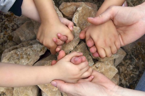 Adult and chilcren holding hands around stone circle wishing desire