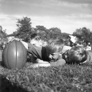 Rugby 1940. Three young rugby players lying in the grass on the rugby field, one holding the rugby