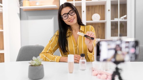 Female vlogger home with smartphone make up products