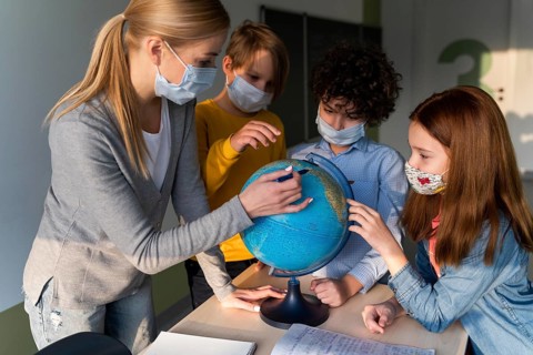 Female teacher with medical mask teaching geography with earth globe class