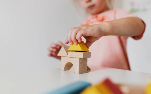 Little child girl playing wooden building blocks at home or kindergarten. Development and
