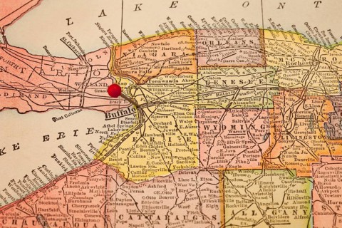 Buffalo and part of New York state on vintage 1920s map with a red pushpin, selective focus