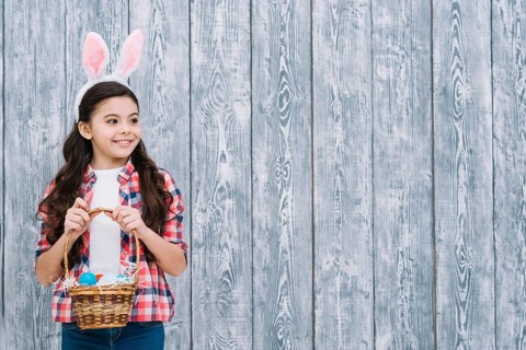 Portrait girl with bunny ears holding easter eggs basket looking away