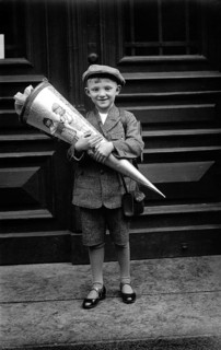 Boy with school cone, 1920s, A boy holds a large school cone in front of a door and smiles