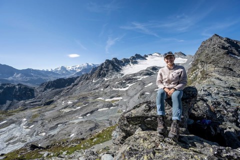 Mountaineer resting on a rock, in rocky mountain landscape, at Col de Prafleuri, Valais Alps, Val