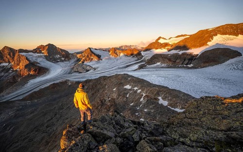 Mountaineers in front of a picturesque high mountain landscape at sunrise with alpenglow, glacier