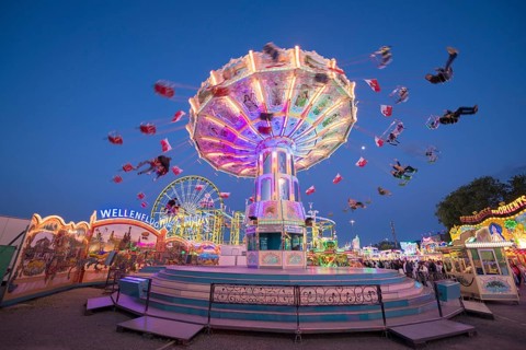 An illuminated chain carousel turns at a fairground at night, chain carousel, spring festival,