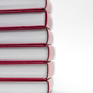 Stacked books with red spines creating a minimalist display against a white background