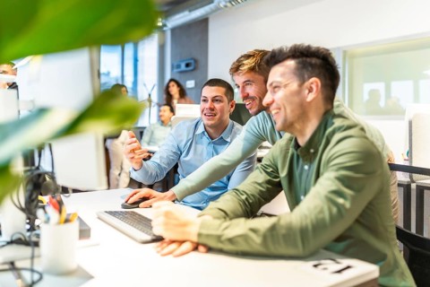 Programmers collaborating on code in a bright, modern office, showcasing teamwork and innovation in