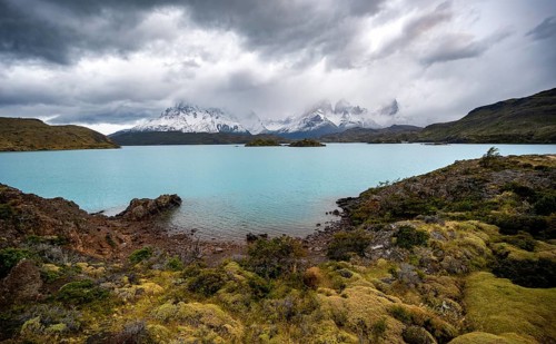 Cloudy mountain range Cuernos del Paine, shore of the blue lake Lago Pehoe in the evening light,