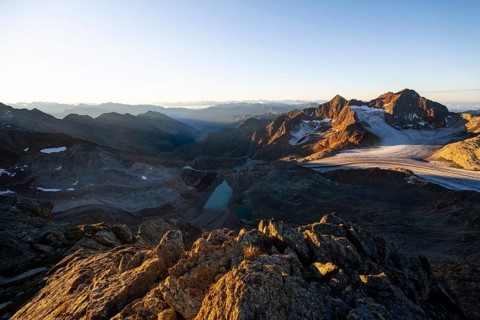 Picturesque high mountain landscape at sunrise with alpenglow, blue glacial lakes, glaciers and