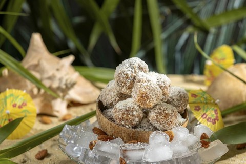 Almond and chocolate confectionery in a coconut on ice cream with umbrellas on sand